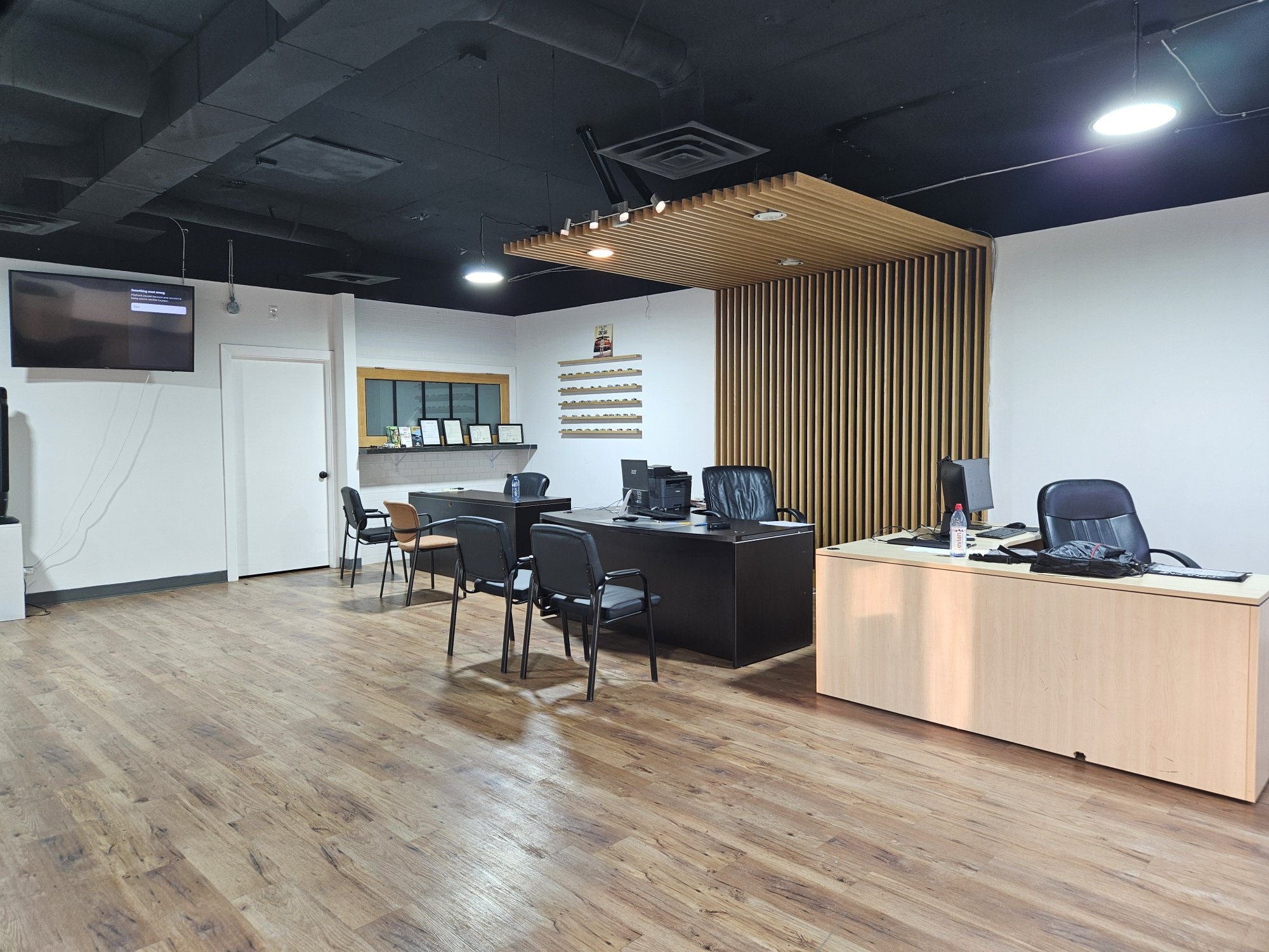 The customer sales office inside Vertex Auto Corp, with desks, visitor chairs, a wall-mounted screen and rows of vehicle key hooks on the wall