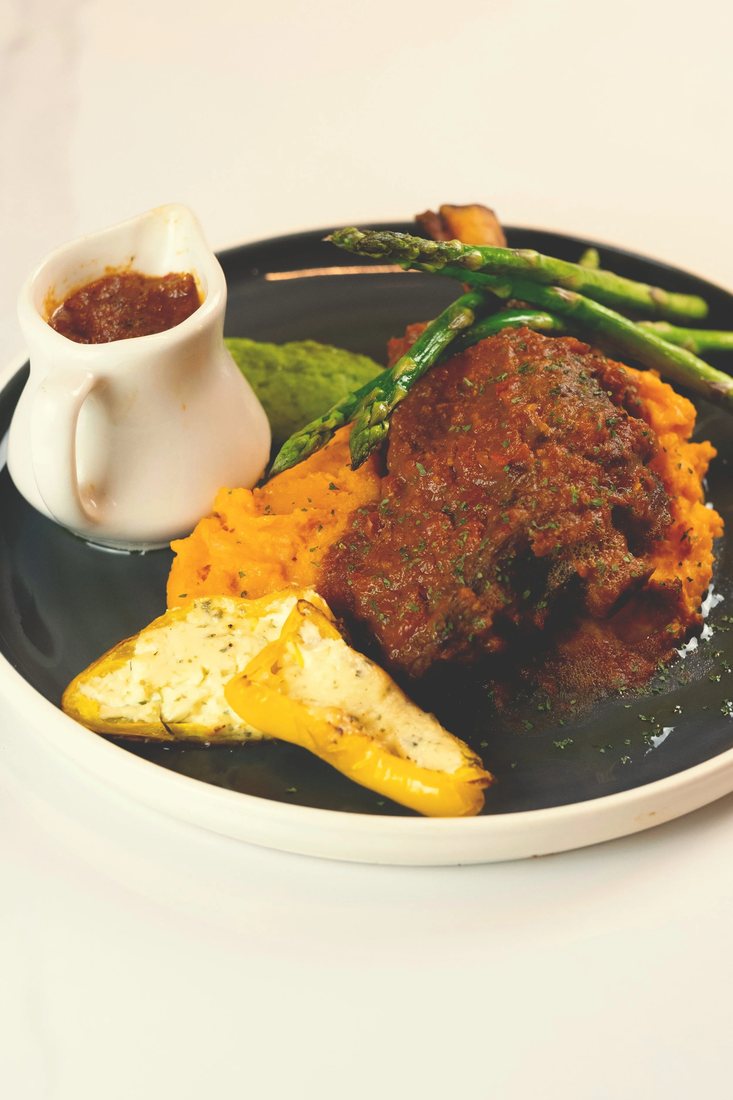 Australian Lamb Caldereta: a braised lamb shank over carrot and potato mash with asparagus and a cheese-stuffed pepper