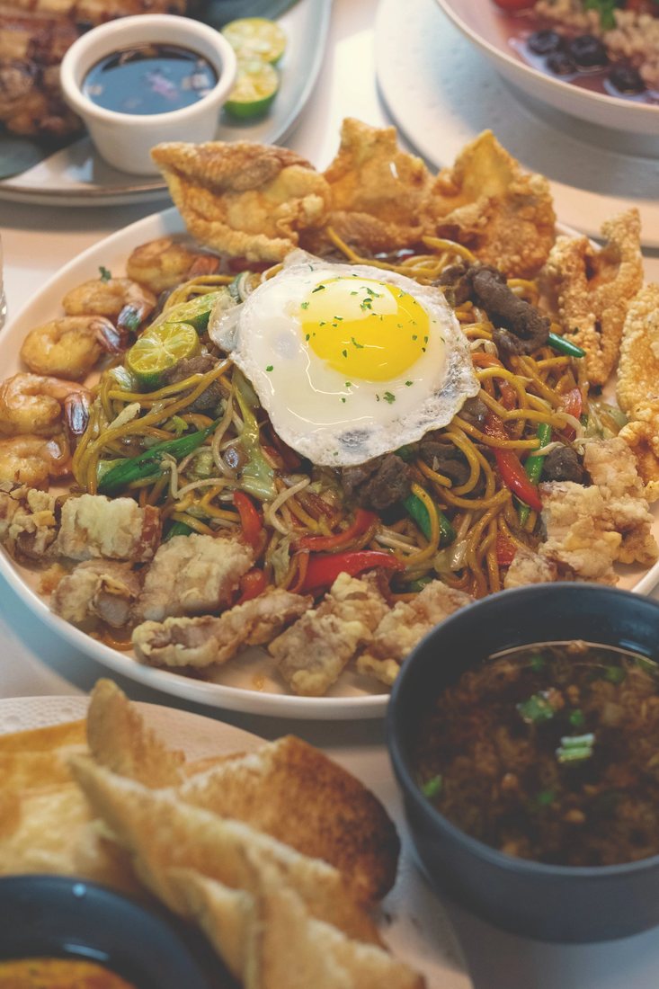 Pancit Batil Patong: stir-fried egg noodles with crispy pork, chicken skin and a fried egg, broth on the side